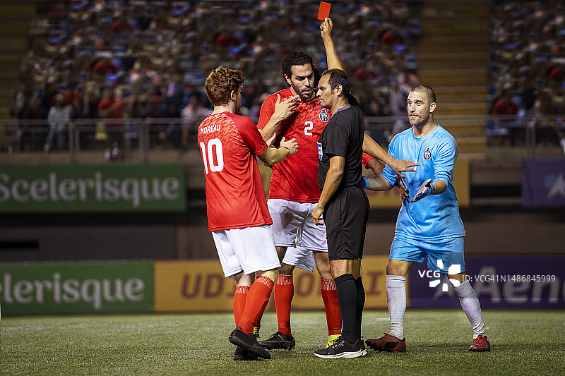裁判严厉地向试图争辩的足球运动员出示红牌图片素材
