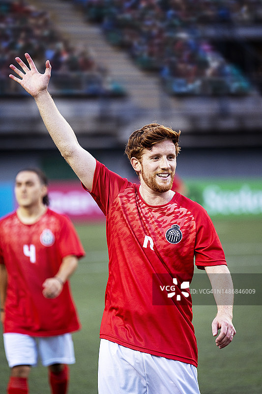 自信的男足球运动员在国际比赛前兴奋地向球迷挥手图片素材