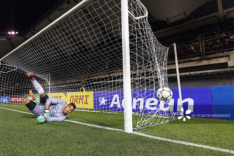 男足球守门员潜水拦截球但未击中，摔倒在球场上图片素材