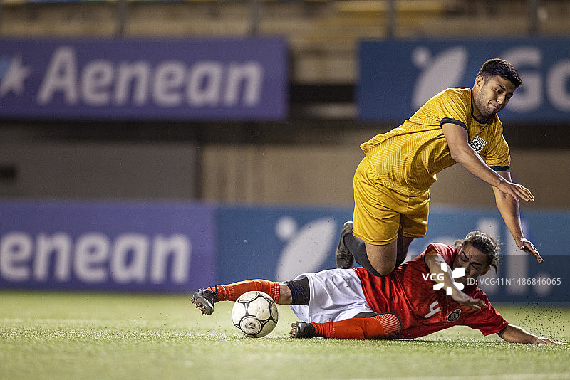 职业足球运动员铲球抢球，对手被绊倒图片素材