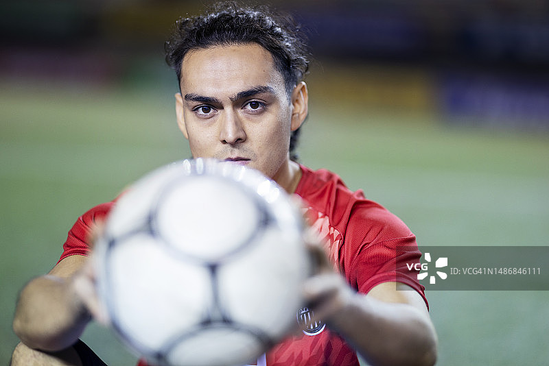 坐在体育场上凝视镜头的足球运动员图片素材