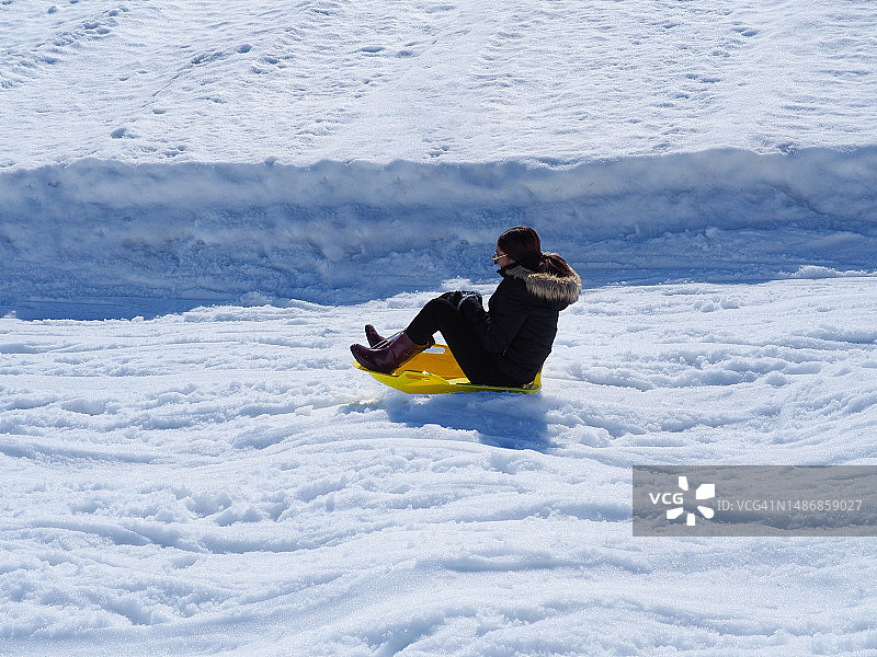 快乐的女孩在日本的雪地里滑雪橇图片素材