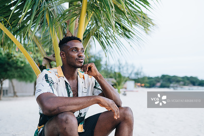 英俊的黑人男子坐在沙滩上图片素材