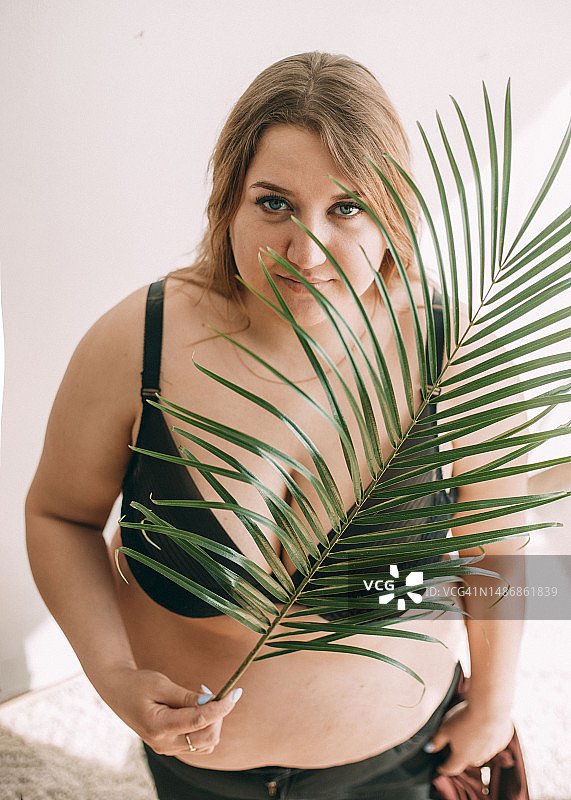 一位面容模糊的加大码女性坐在室内的床上图片素材