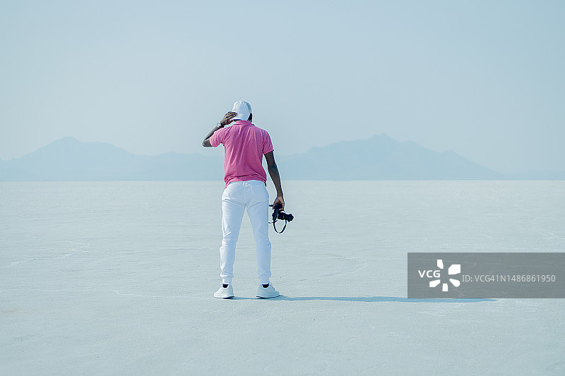 在美国犹他州盐湖城站在白色沙滩上，手持相机的年轻男子肖像图片素材