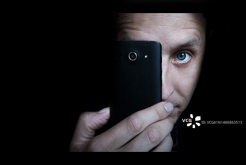 特写：男子手持手机，黑色背景图片素材
