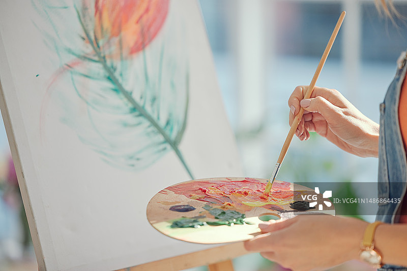 艺术绘画：女人在客厅的画布上绘画，追求创作自由、爱好或活动。创意：女画家正在创作一幅色彩鲜艳的艺术作品图片素材