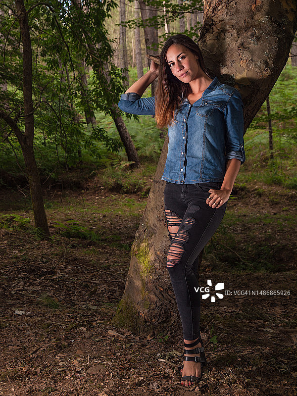 年轻女子靠在树干旁的肖像图片素材