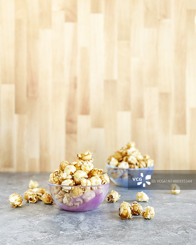 灰色木桌上的焦糖爆米花碗图片素材