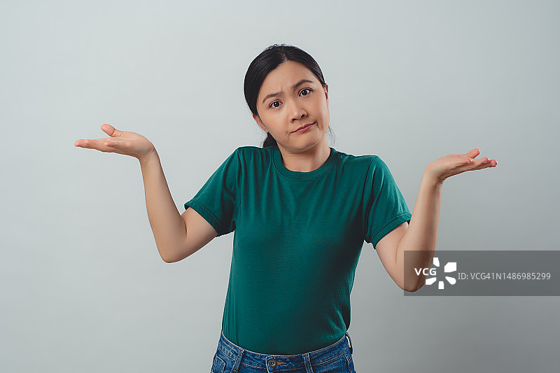 亚洲女人感到恼火，耸着肩膀孤立地站在背景前图片素材