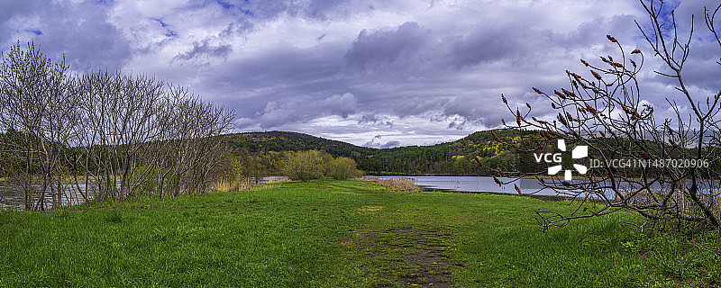 美国佛蒙特州哈特福德奥塔奎奇河畔，暴雨过后被洪水淹没的河岸和充满活力的春季绿色图片素材