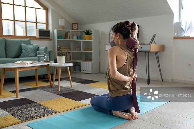 女人在家用阻力带做瑜伽图片素材