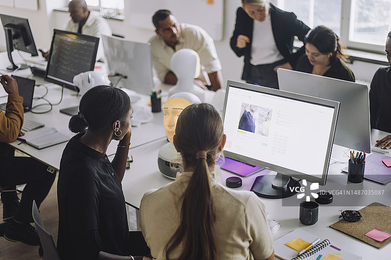 在创新实验室的桌子上，多元种族女性博士生讨论电脑图片素材