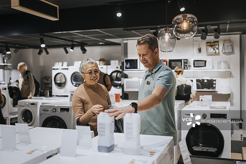 男销售员在电子产品商店建议老年妇女购买电器图片素材