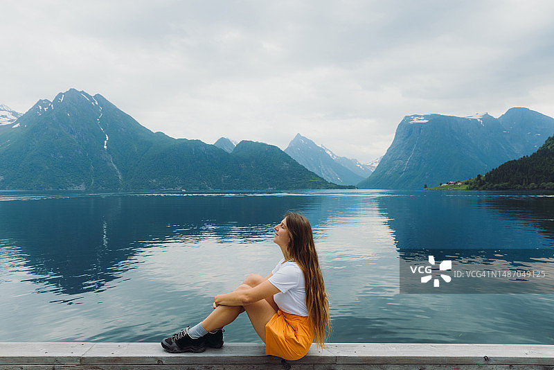快乐的女人在挪威沉思峡湾景色侧面照图片素材