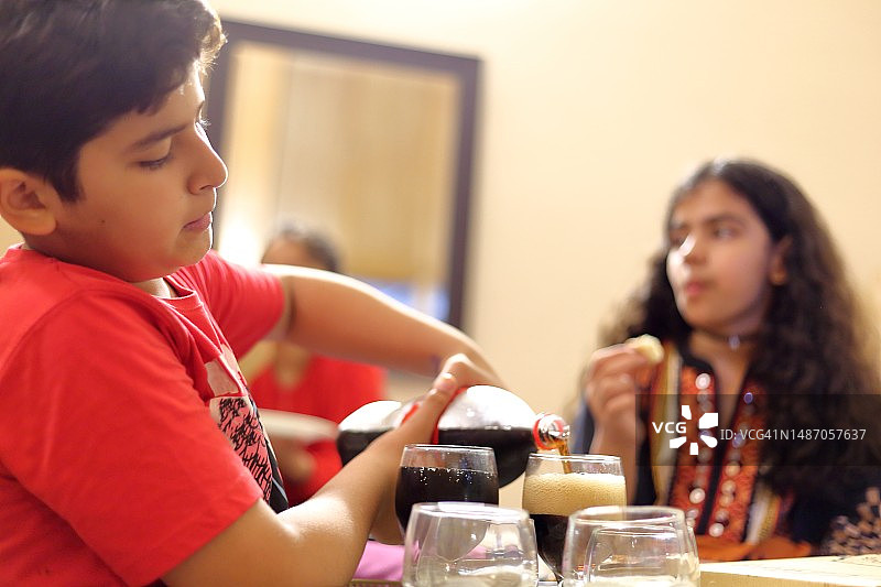 男孩往玻璃杯里倒冷饮图片素材