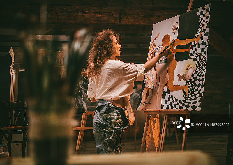 年轻的女艺术家在她的工作室工作图片素材