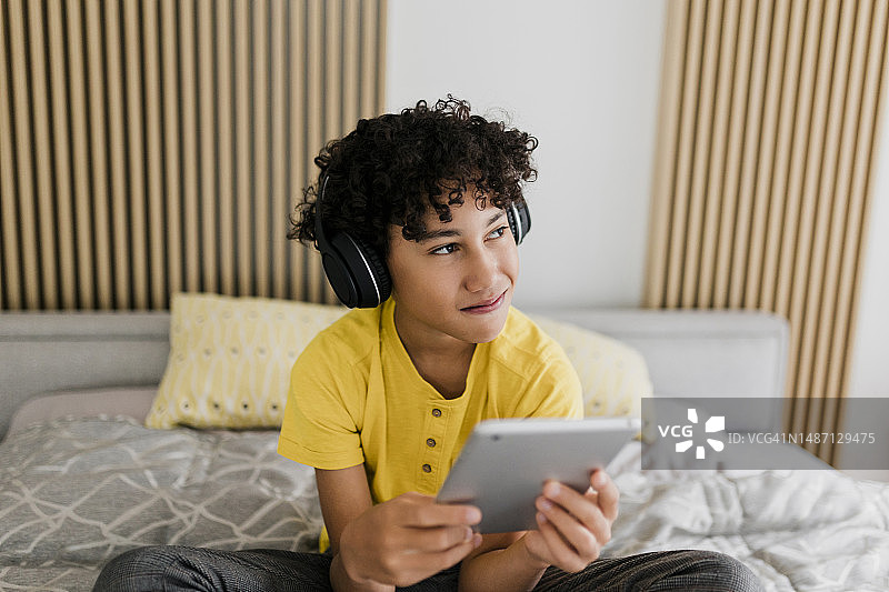 男孩在卧室里使用平板电脑图片素材