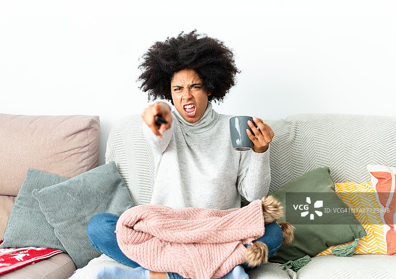 愤怒的非洲女人在家使用遥控器图片素材