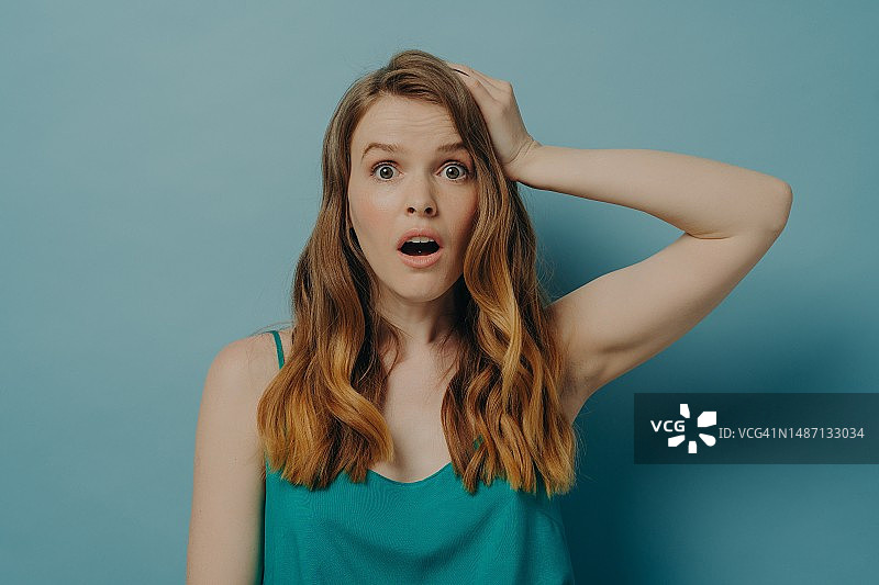 震惊的白人女性张大嘴巴，在蓝色背景下（俄罗斯）图片素材