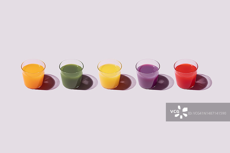 粉色背景上的一排彩色果汁图片素材