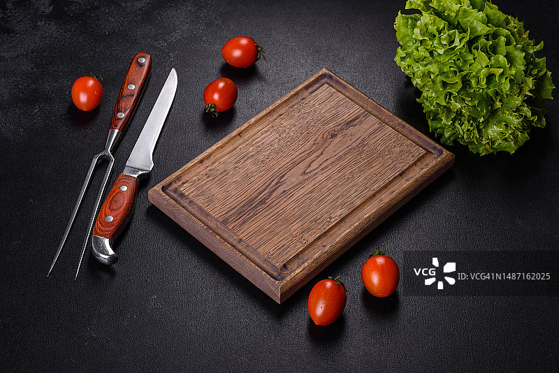 深色混凝土背景上的棕色长方形木制砧板，带有盐和香料，罗马尼亚图片素材