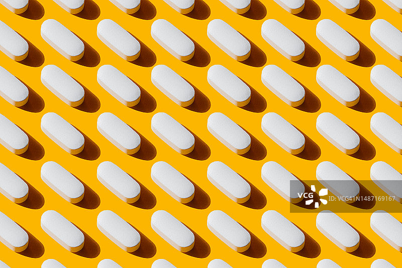 白色胶囊药丸中的维生素图案，黄色背景图片素材