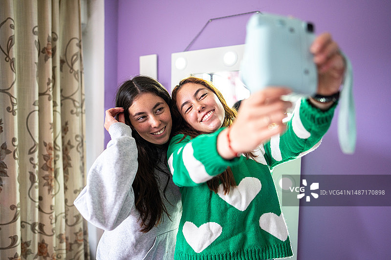 在卧室用相机自拍的双胞胎姐妹图片素材