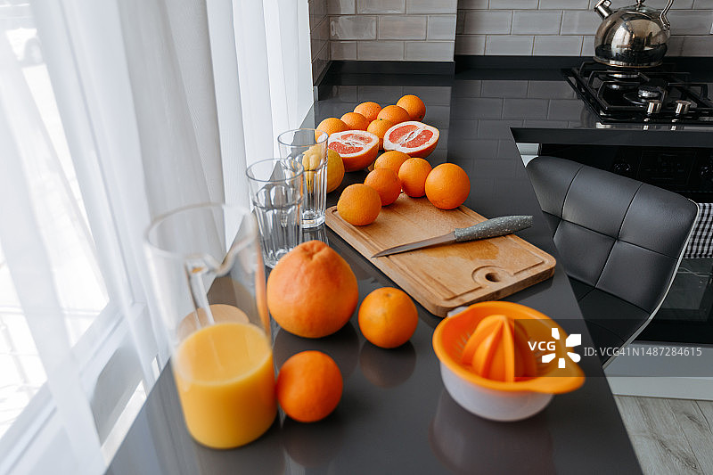 灰色石桌上新鲜鲜榨橙汁壶与鲜橙图片素材