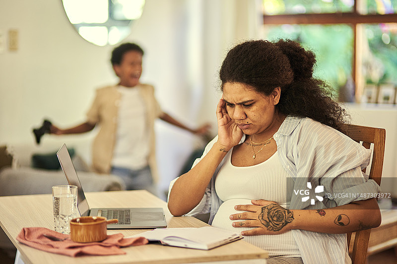 孕妇感到压力和头痛，疲惫不堪，孩子在家过度活跃，感到疼痛和疲劳。怀孕的母亲患有偏头痛、疾病，因健康问题和噪音而精疲力竭图片素材