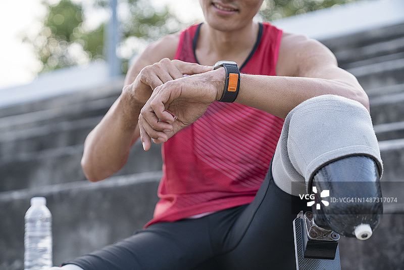 正在看智能手表的残疾人运动员，坐着休息图片素材