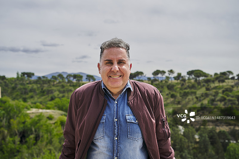 在自然背景下微笑并看向镜头的男人图片素材