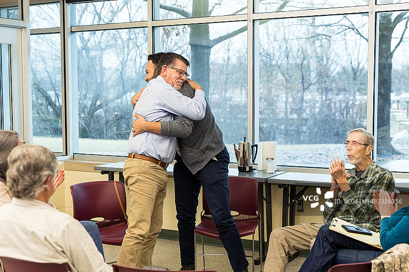 中年男人在团体治疗中拥抱年轻人图片素材