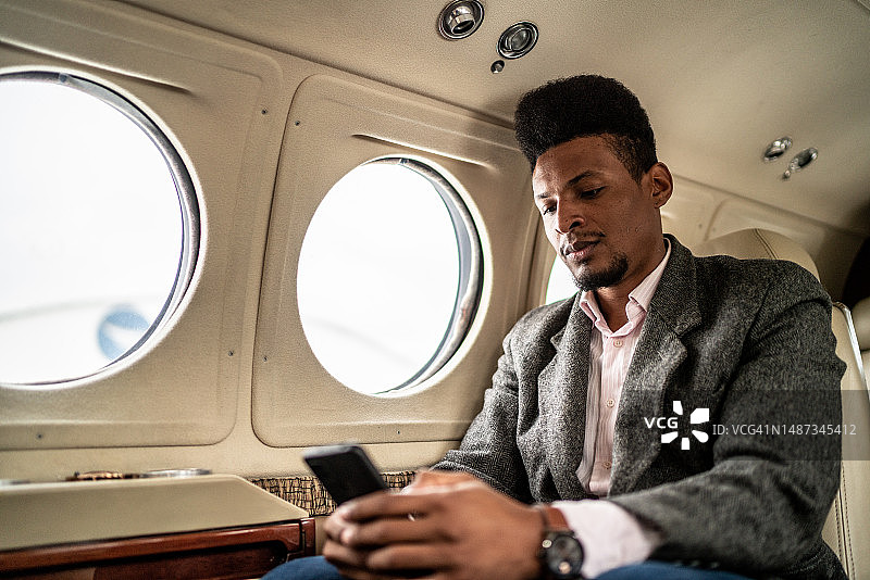 中年商人在私人飞机上使用手机图片素材