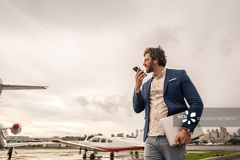 中年商人于机场机库行走时发送语音消息图片素材