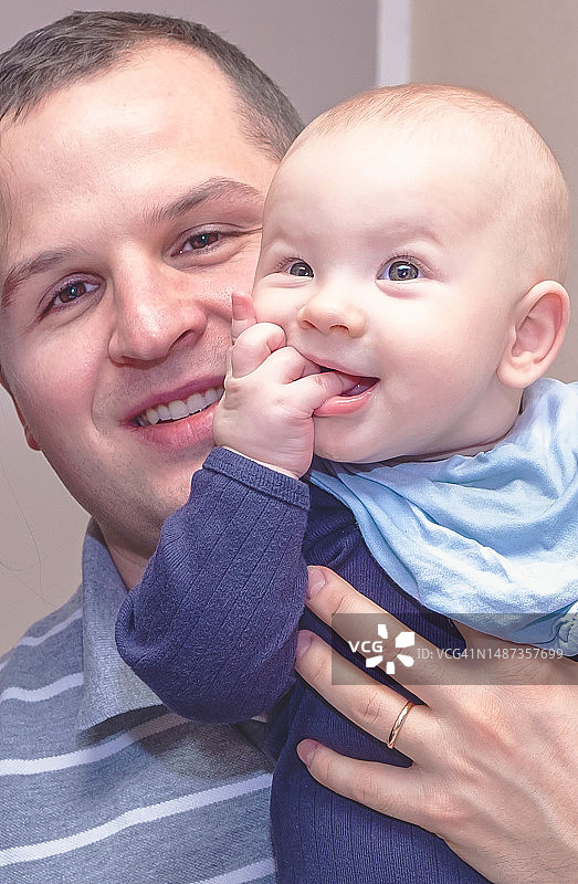 年轻白人父亲怀抱吮吸拇指的婴儿图片素材
