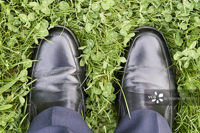 黑色正装鞋踩草地，裤腿可见图片素材