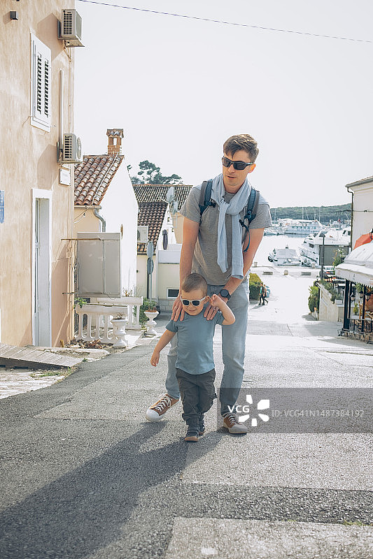 晴天里，爸爸和孩子走在城市街道上图片素材
