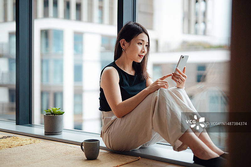年轻的亚洲女人用智能手机进行网上购物图片素材