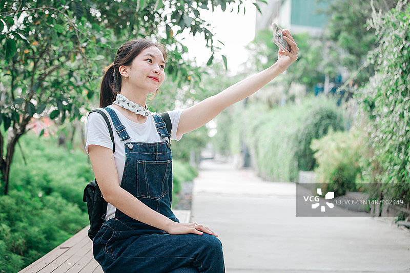 年轻亚洲女人公园手机自拍图片素材