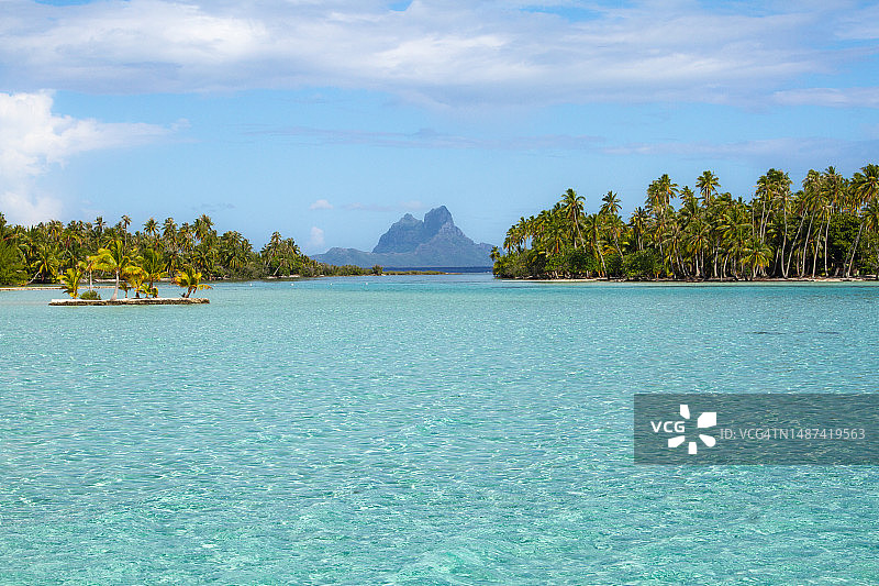 从塔哈岛拍摄的波拉波拉岛水晶般清澈的泻湖景观，周围环绕着棕榈树图片素材