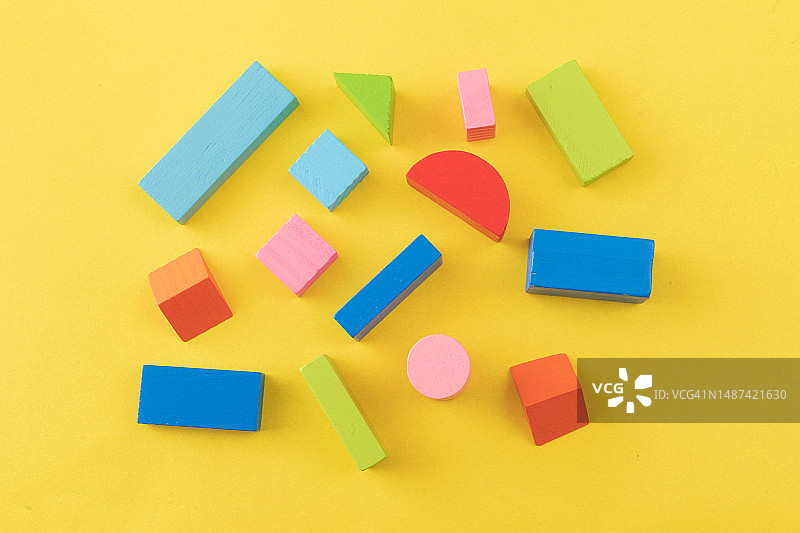 黄色背景上的彩色木制玩具积木图片素材