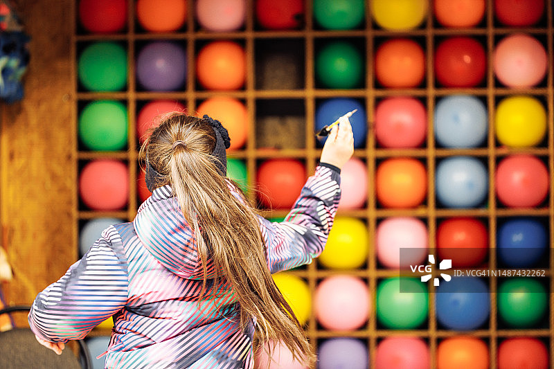 游乐园里玩气球飞镖射击的女孩图片素材