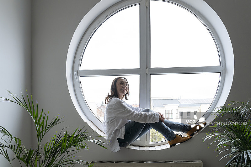 沉思的女商人坐在圆形窗台上图片素材