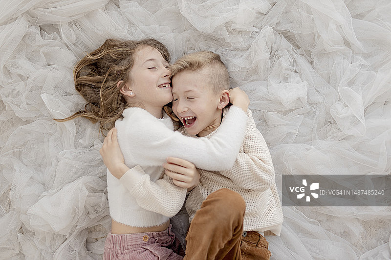 兄妹俩躺在薄纱网上图片素材