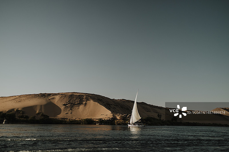 日落时分尼罗河上航行的三角帆船图片素材