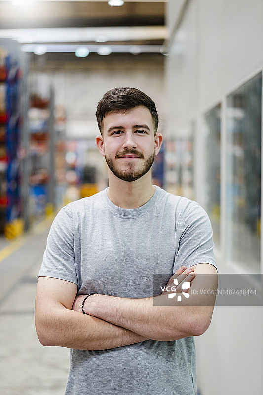 微笑的年轻员工在工厂里双臂交叉站立图片素材