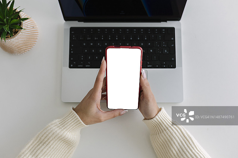 年轻女子使用智能手机的俯视图。用于图形展示或广告的空白屏幕手机。复制空间。图片素材