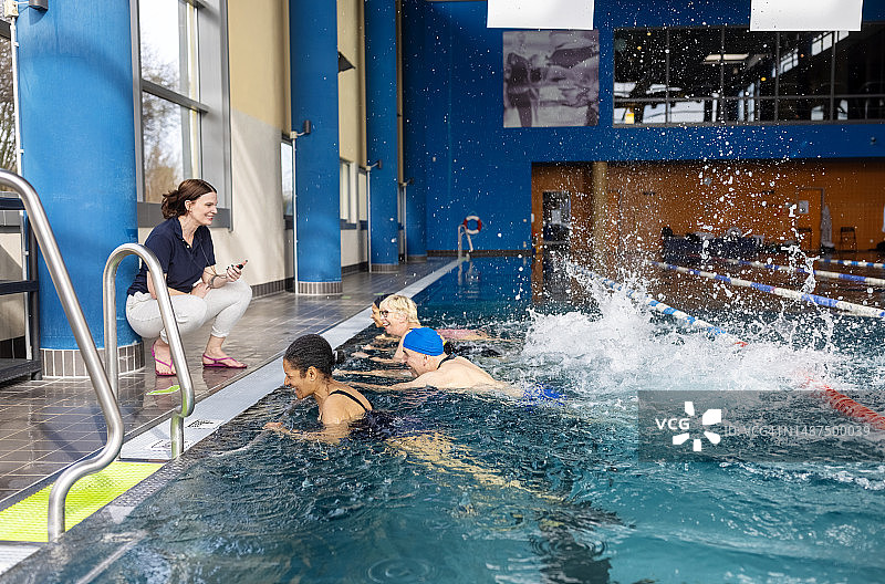 一群老年人在游泳池里与教练一起锻炼图片素材