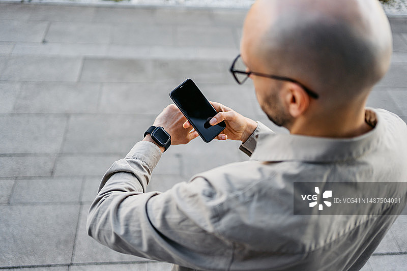 在户外使用手机和智能手表的年轻男人图片素材